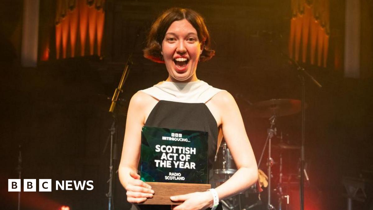 Alice Faye wearing a black and white dress holding the trophy for BBC Introducing Scottish Act of the Year.