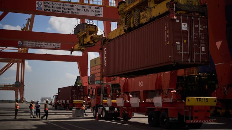 Dockworkers unload cargo containers into trucks at Umm Qasr Port, a deep-water port, in the city of Umm Qasr, Iraq, Friday, March 27, 2026.