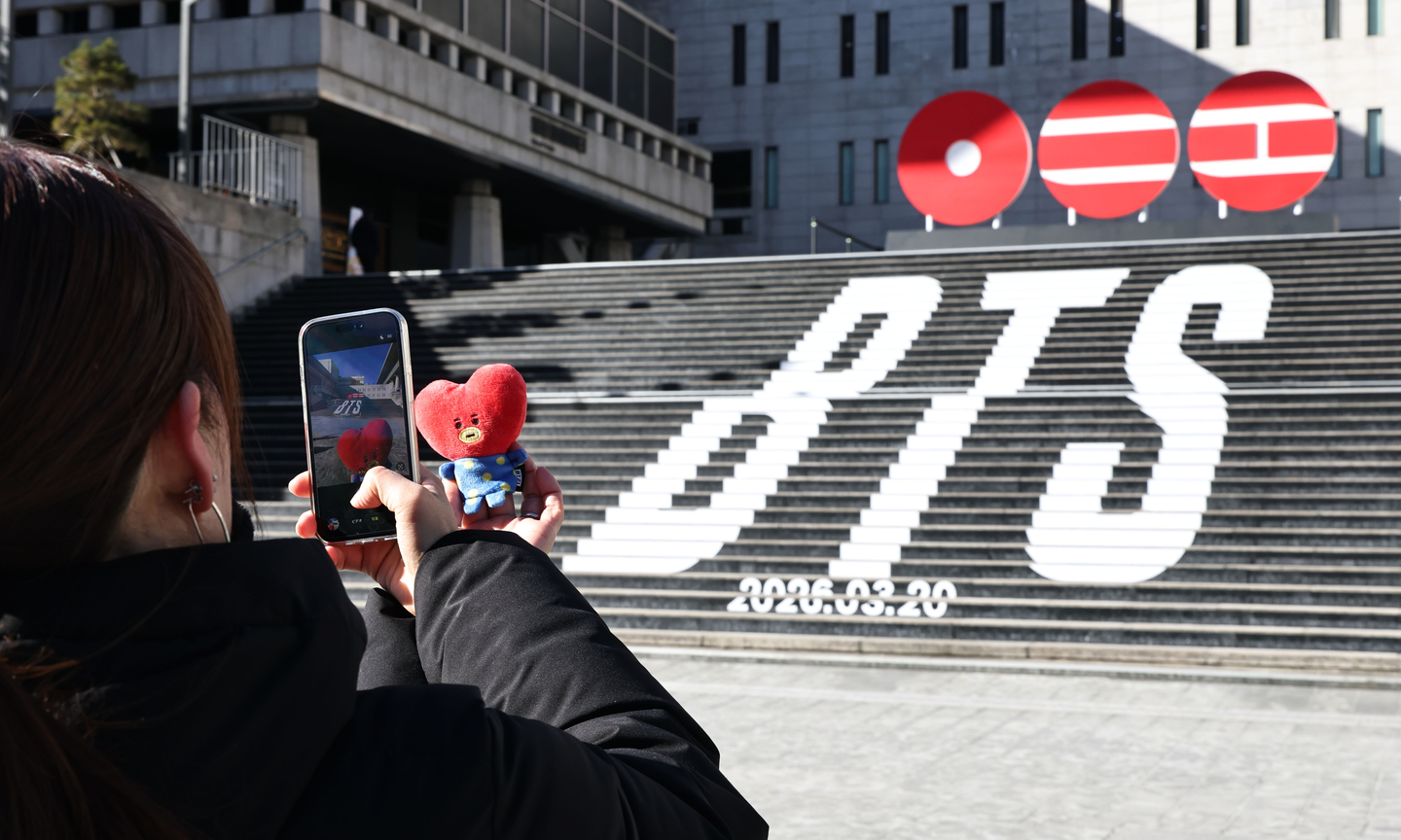 A tourist takes a photo of a promotional event announcing boy band BTS's new music and concerts in Jongno District, central Seoul, on Jan. 22, 2026. [YONHAP]