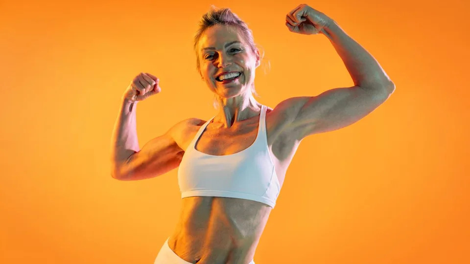 A woman flexing her biceps and smiling.