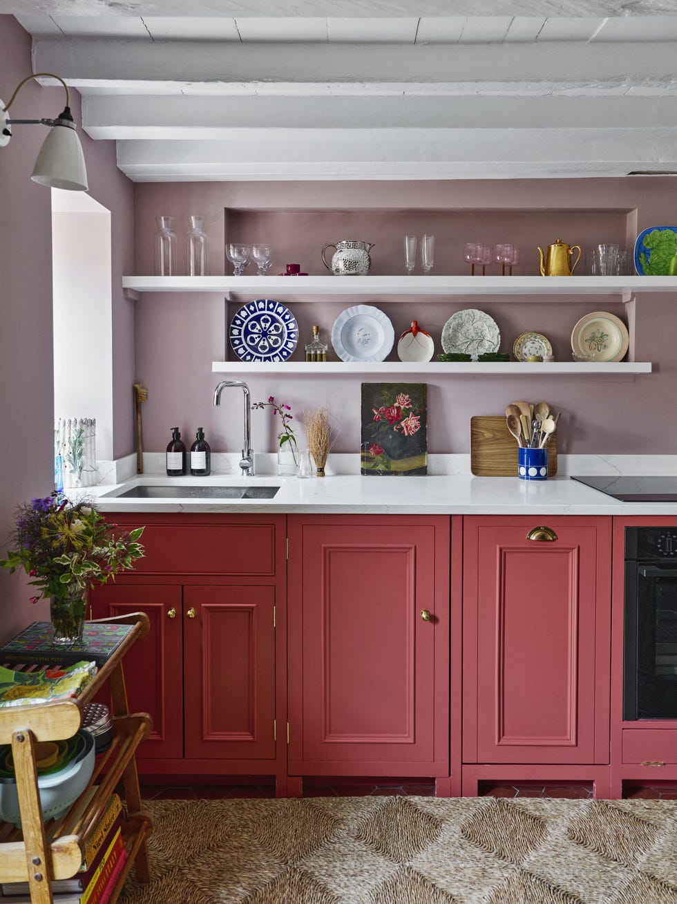 Compact galley kitchen with open shelving and red cabinetry small galley kitchen with pink walls, red cabinets, open shelves displaying ceramics and a white worktop