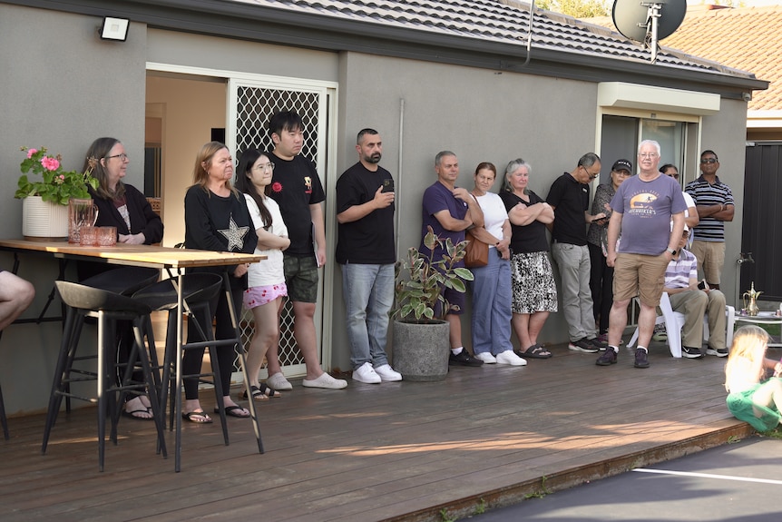 A group of people outside on a deck listening to real estate agents