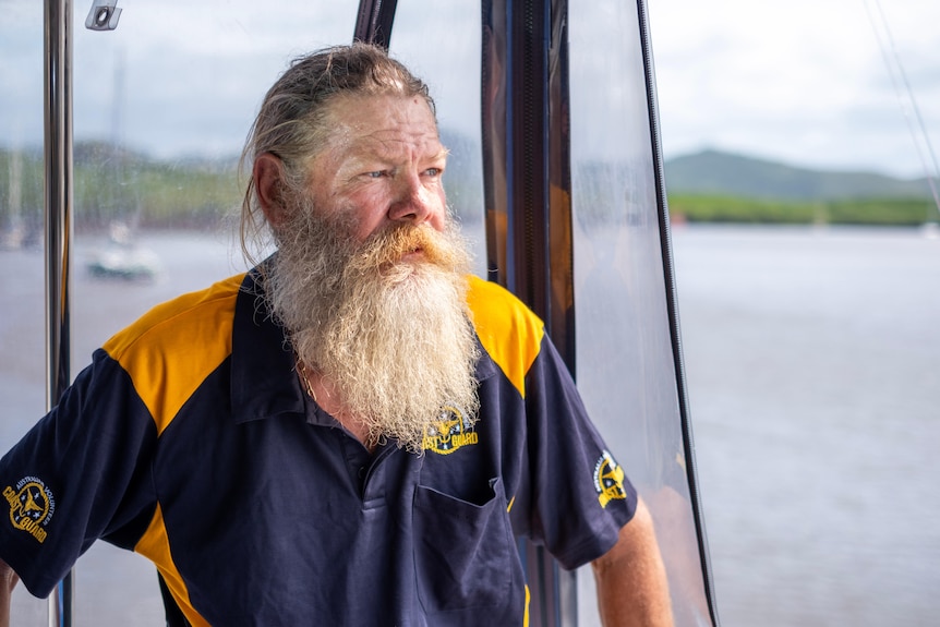 Man with beard on boat looking out to sea.
