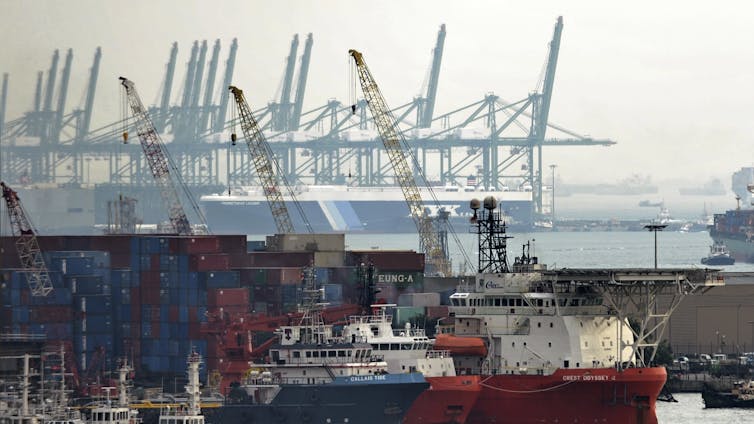 Cranes are seen next to a large ship.
