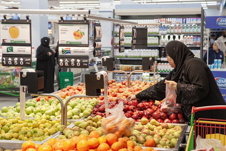 qatari women shopping in a supermarket selling imported fruit and vegetables.