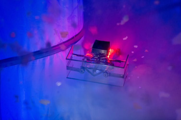 a small boxy device with lights surrounded by small white particles