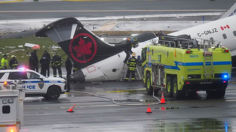 Firefighters and investigators examine the site, Monday, March 23, 2026, where an Air Canada jet came to rest after colliding with a Port Authority firetruck at LaGuardia Airport.