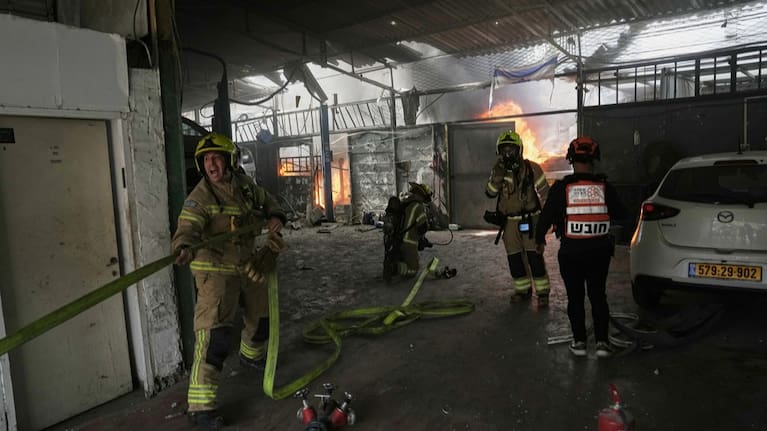 Firefighters try to extinguish a fire at a damaged workshop struck by an Iranian missile in Petah Tikva, Israel.