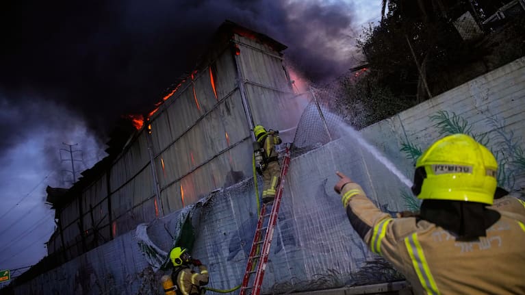 Firefighters try to extinguish flames at the site of a direct hit by an Iranian missile strike in Holon, central Israel.