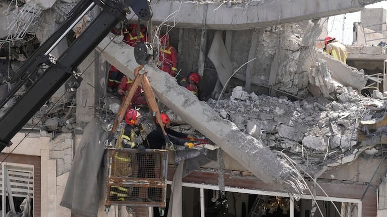First responders work to remove a body from the rubble of a residential building hit in an overnight US-Israeli strike in Tehran, Friday, March 27, 2026.