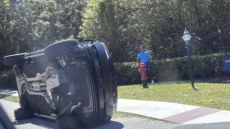 Golfer Tiger Woods stands by his overturned vehicle in Jupiter Island