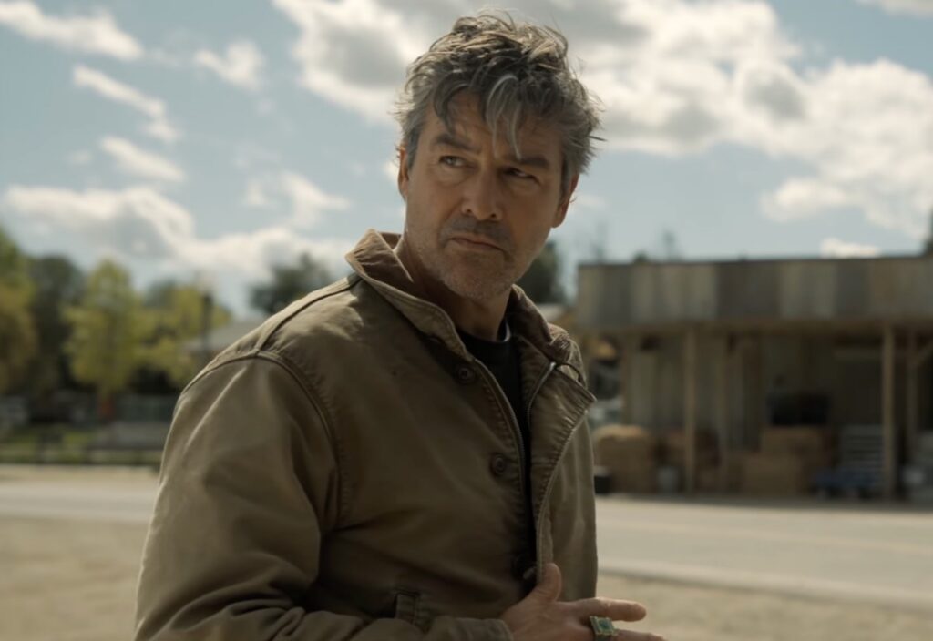 closeup of a scruffy middle aged man standing on a rural town street