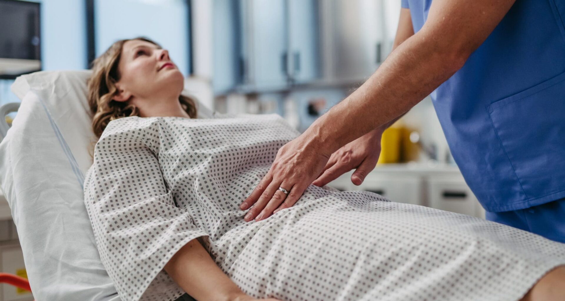 ER doctor palpating woman's abdomen, using hands and steady pressure.