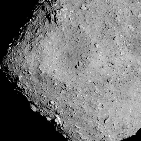 Hayabusa-2 image of the asteroid Ryugu as seen from a distance of 3.7 miles. A particularly large crater is visible near the center of the image. Image credit: JAXA / University of Tokyo / Kochi University / Rikkyo University / Nagoya University / Chiba Institute of Technology / Meiji University / University of Aizu / AIST.