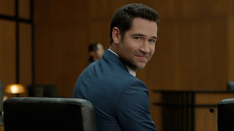 Mickey Haller (Manuel Garcia-Rulfo) looks back smiling in a courtroom in The Lincoln Lawyer
