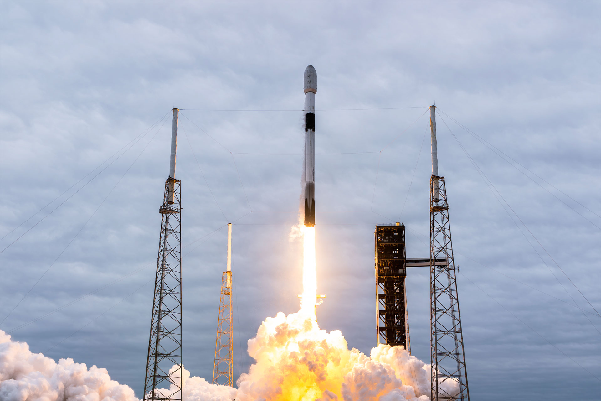 a white and black rocket lifts off into a cloudy sky on its way to low Earth orbit