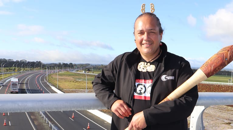 Jo'el Komene in front of the bridge barriers that have a tāniko design which is a pattern often seen on korowai bands worn by chiefs.