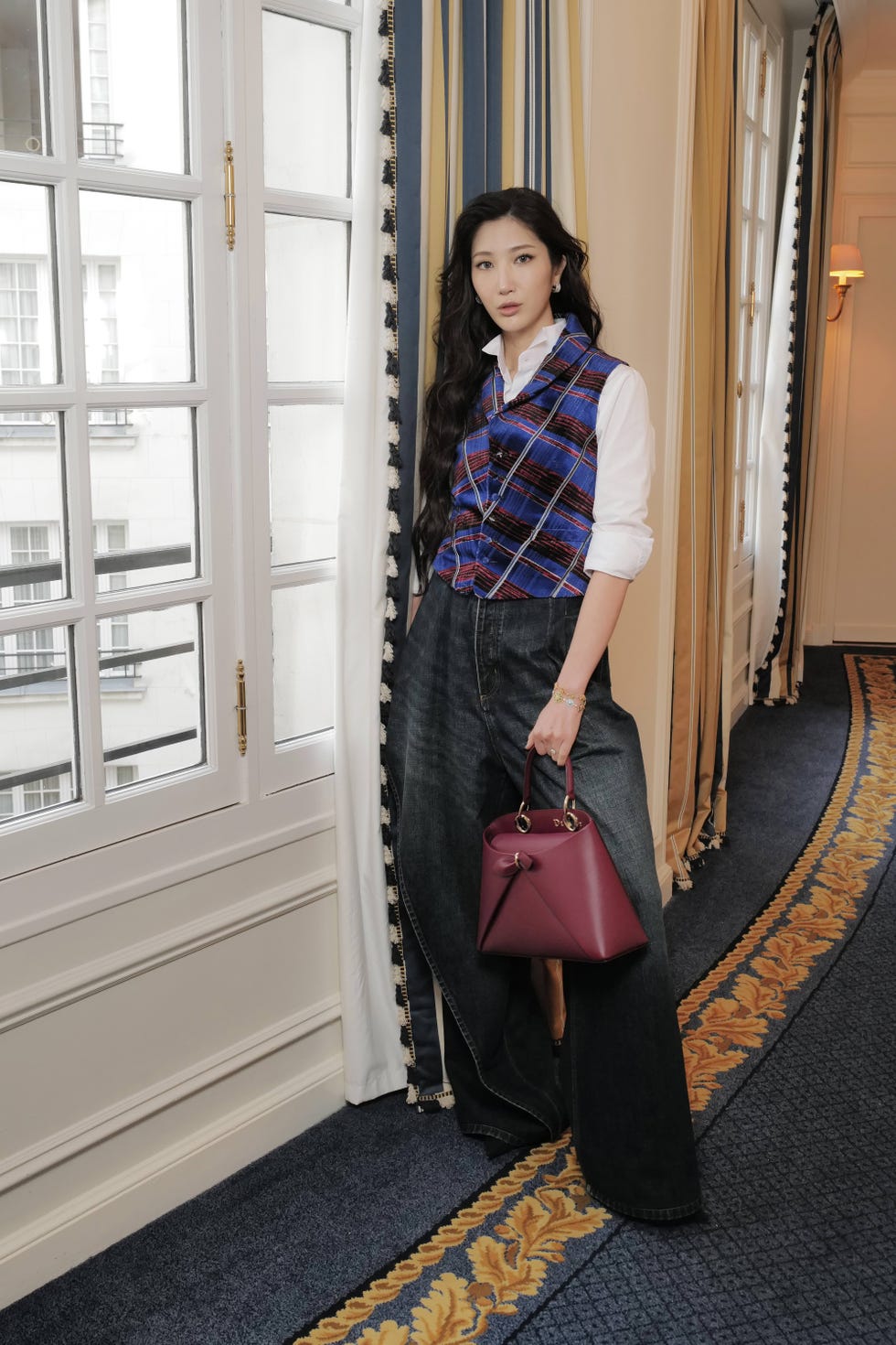 fashionable individual standing by a window showcasing a stylish outfit