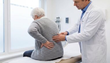 Elderly woman with back pain examined by doctor in medical clinic.