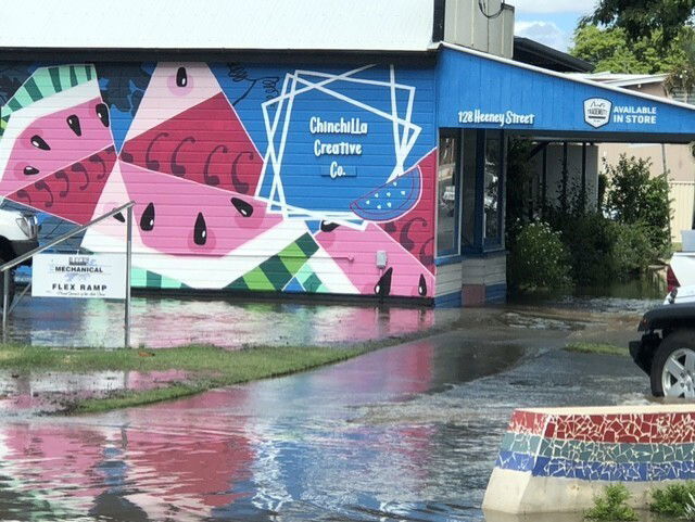A hall with watermelons painted on it and flood water rising above the street. 