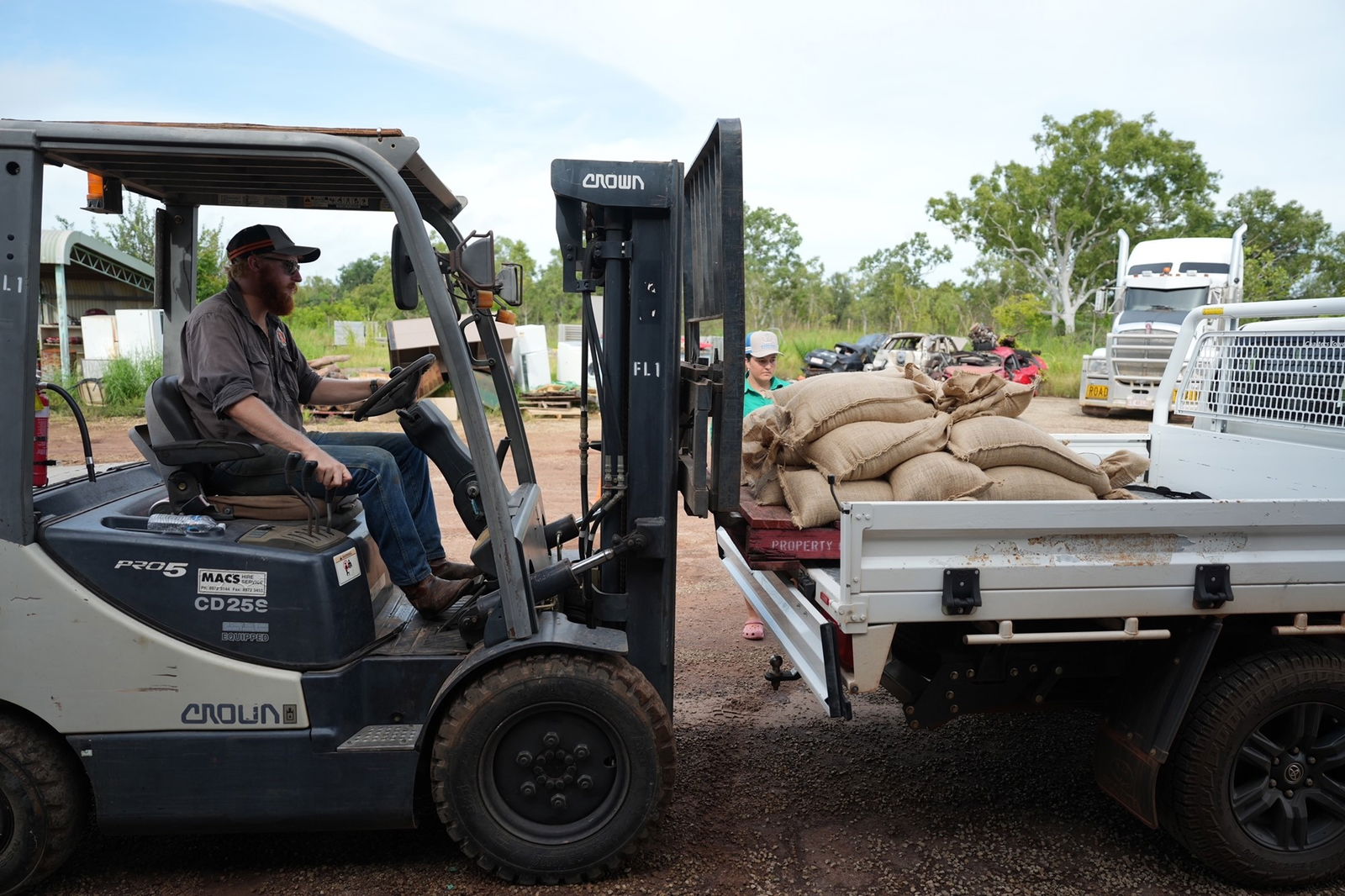 A man on forklift, which is loading sandbags onto the back of a ute.