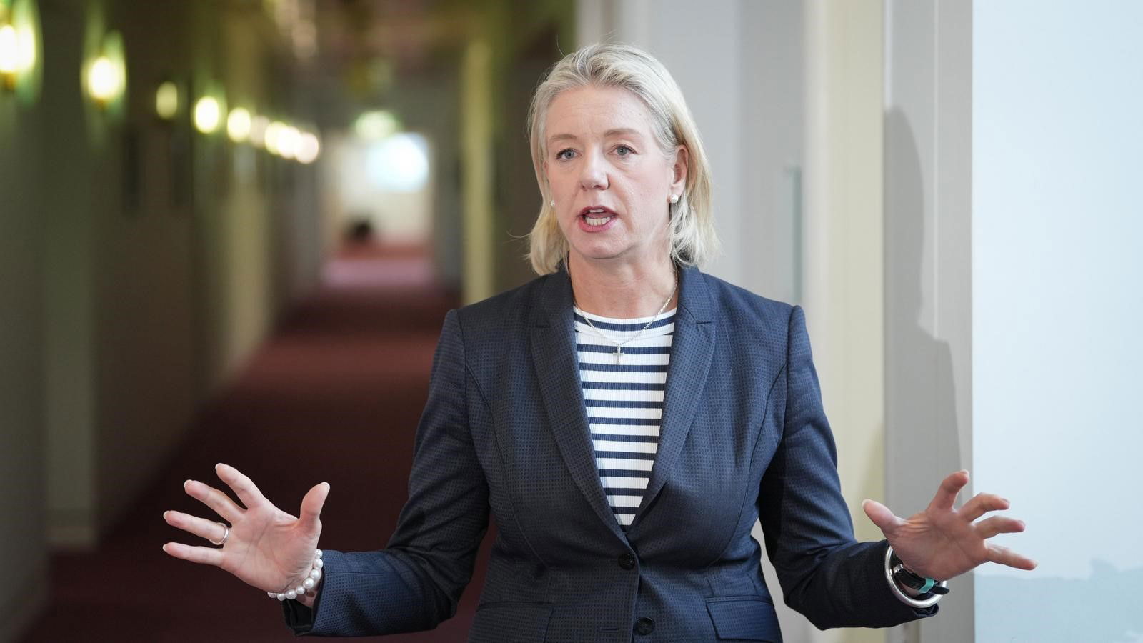 Bridget McKenzie raises her hands while talking to the media.