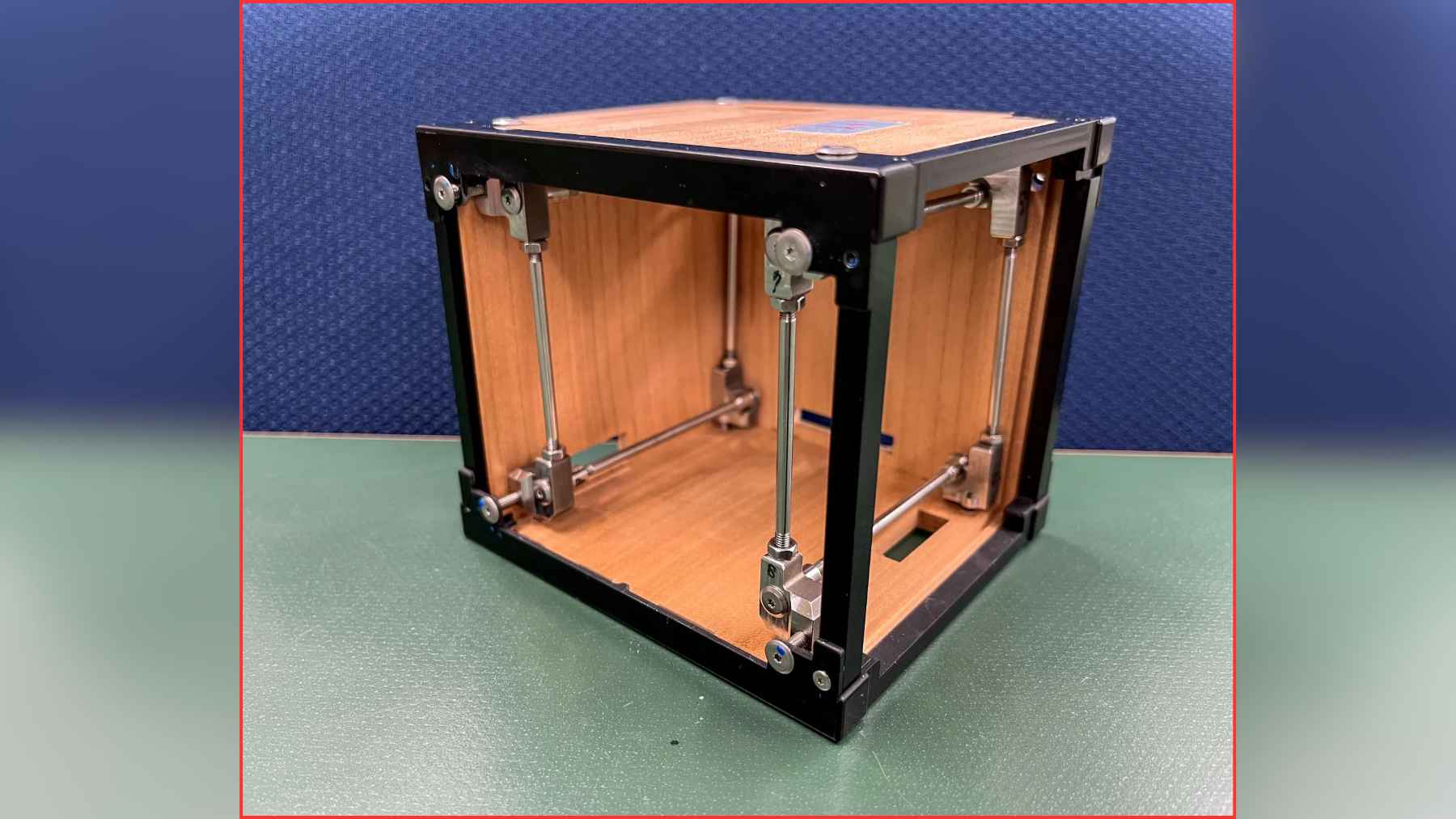 LignoSat wooden cube satellite prototype with metal supports, illustrating Japan’s experiment to reduce orbital debris with wood.