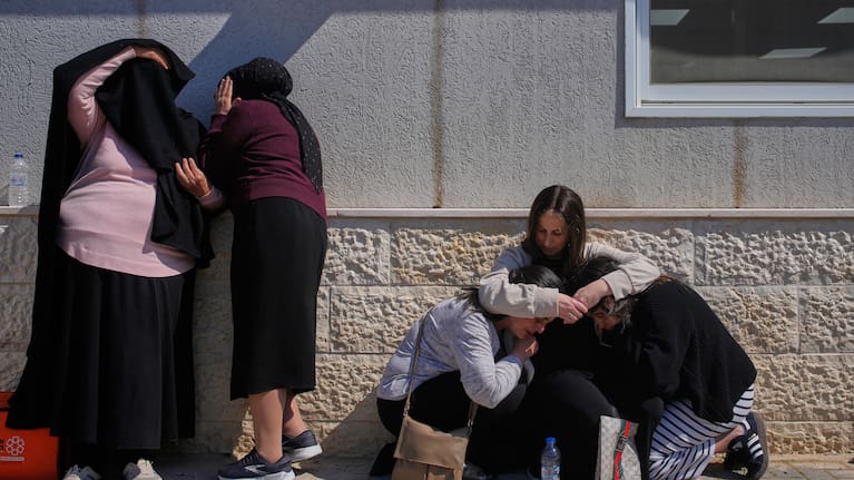 Mourners take cover while air-raid sirens warn of incoming missiles launched by Iran toward Israel during the funeral of Sarah Elimelech and her daughter Ronit who were killed in an Iranian missile attack, in Beit Shemesh, Israel, Monday, March 2, 2026. 