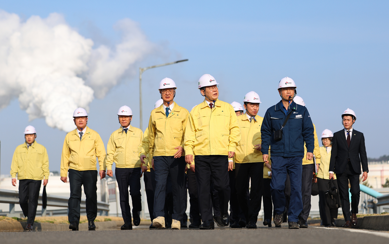 President Lee Jae Myung inspects crude oil storage tanks after holding an on-site roundtable with representatives of LG Chem, Lotte Chemical, Hanwha TotalEnergies Petrochemical, and Hyundai Chemical at a petroleum reserve facility operated by the state-run Korea National Oil Corp. in Seosan, South Chungcheong Province, Thursday. (Yonhap)
