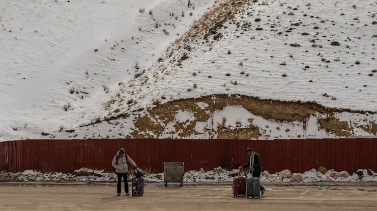 People, mostly Iranians who crossed from Iran through the Kapikoy border crossing, stand with luggage in Türkiye's eastern Van province.