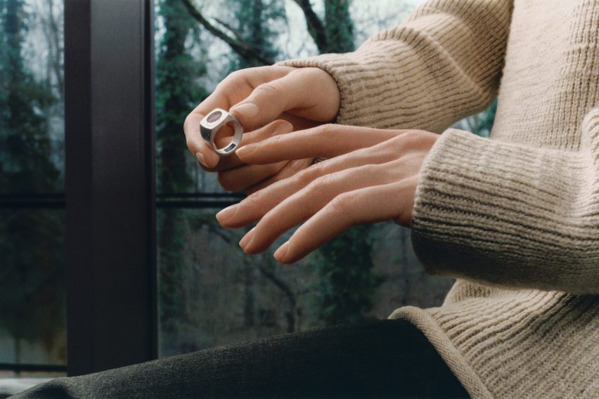 Photo of a person's hands as they slip the silver Quartz ring on one finger