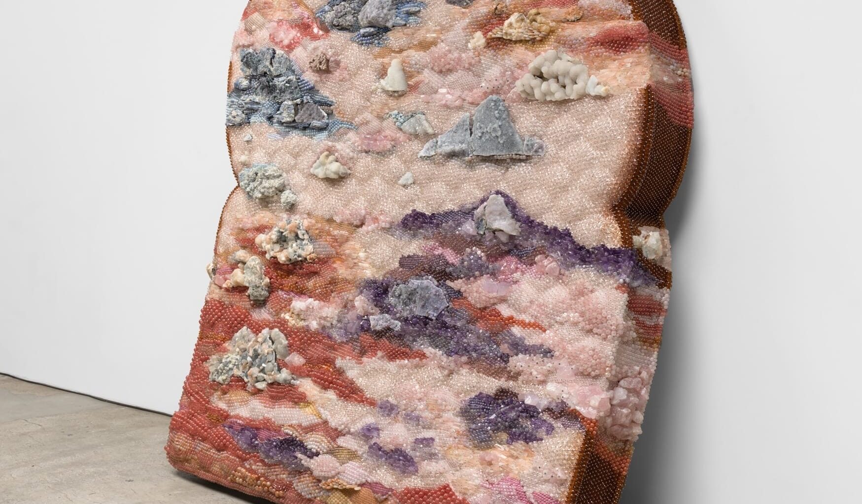 A sculpture of an oversized piece of moldy bread made from beads