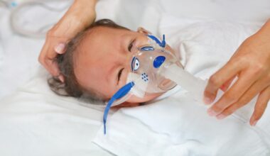 Sick baby boy on a hospital bed applying inhale medication to cure RSV.
