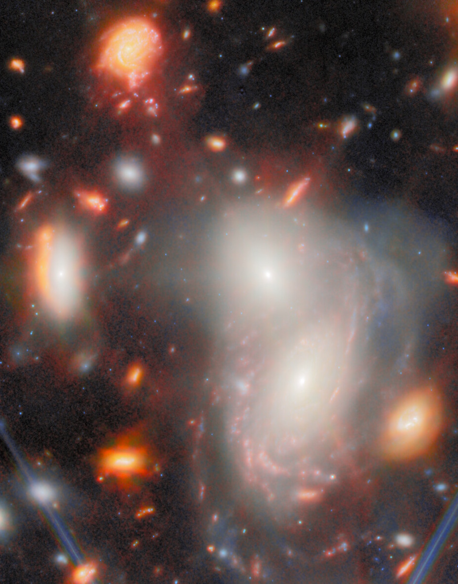 A cluster of bright and colorful galaxies with spiral structures and glowing regions, revealed by the JWST’s most extreme gravitational lens, set against a dark space background dotted with stars.
