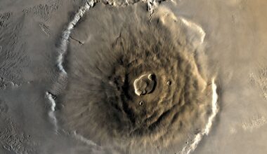A close up of Olympus Mons on the surface of Mars, its structure a pile of brown lava in a large circular mount on the surface of the planet