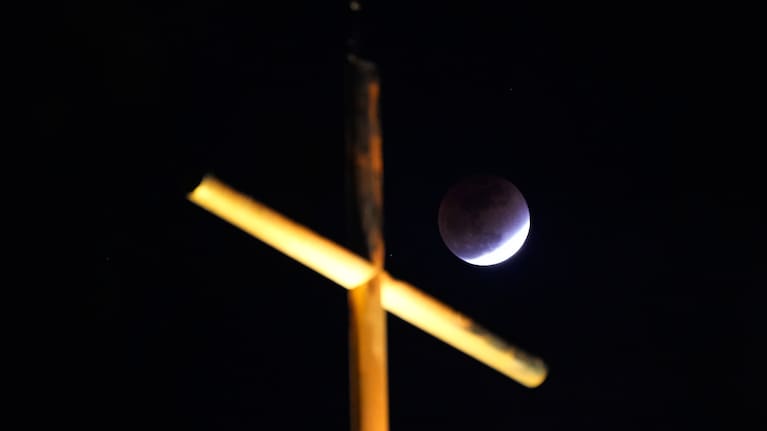 A total lunar eclipse is seen behind a cross over a church in Seoul, South Korea, Tuesday, March 3, 2026.