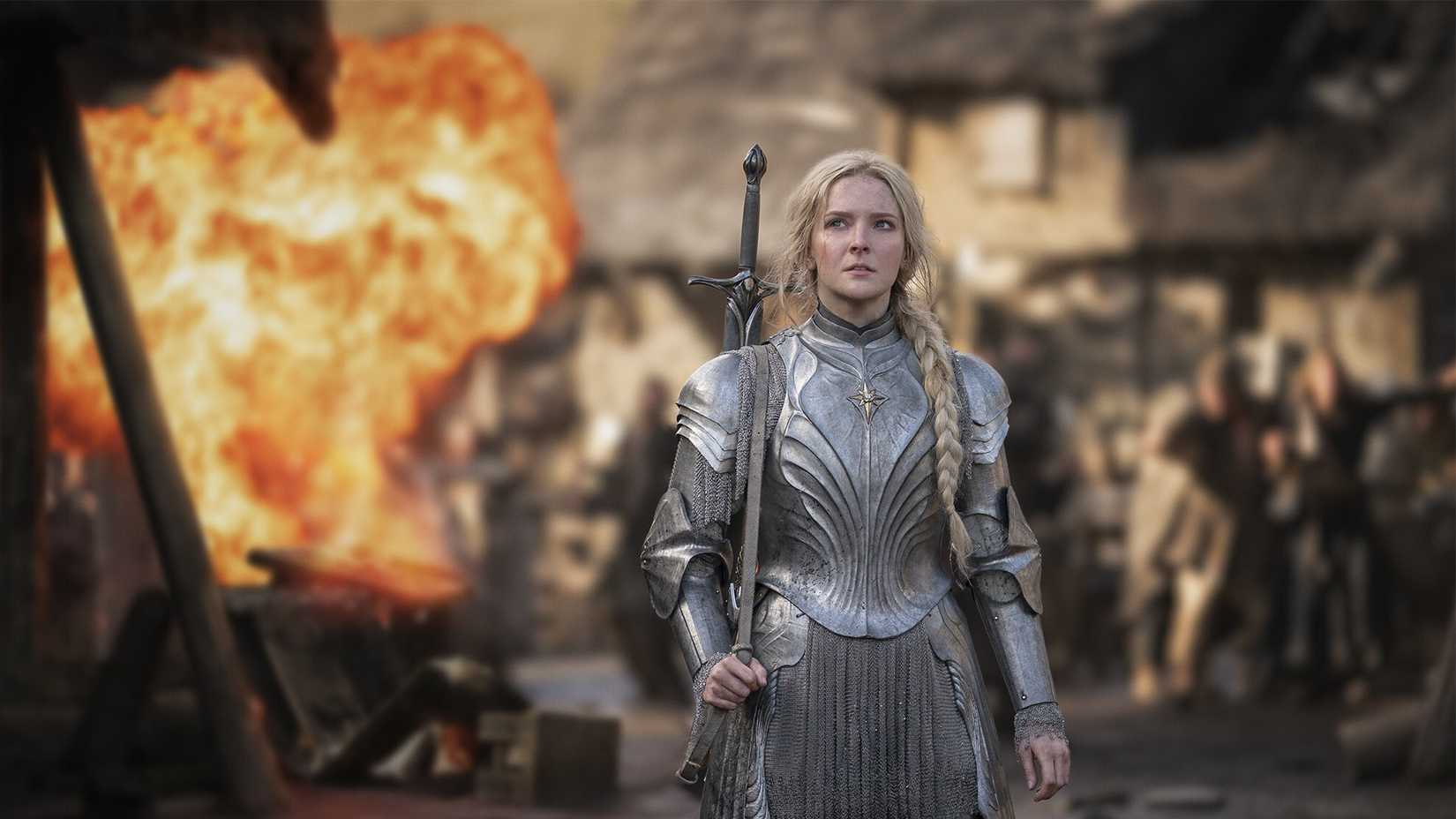 Morfydd Clark as Galadriel holding a sword with her back to a fireball in The Lord of the Rings: The Rings of Power