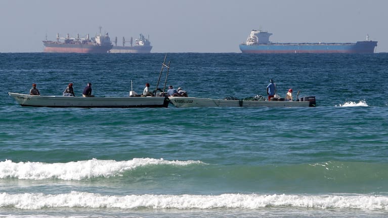 Fishermen work in front of oil tankers south of the Strait of Hormuz. 