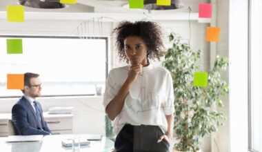 An investor stands in an office, looking at sticky notes placed on a wall.