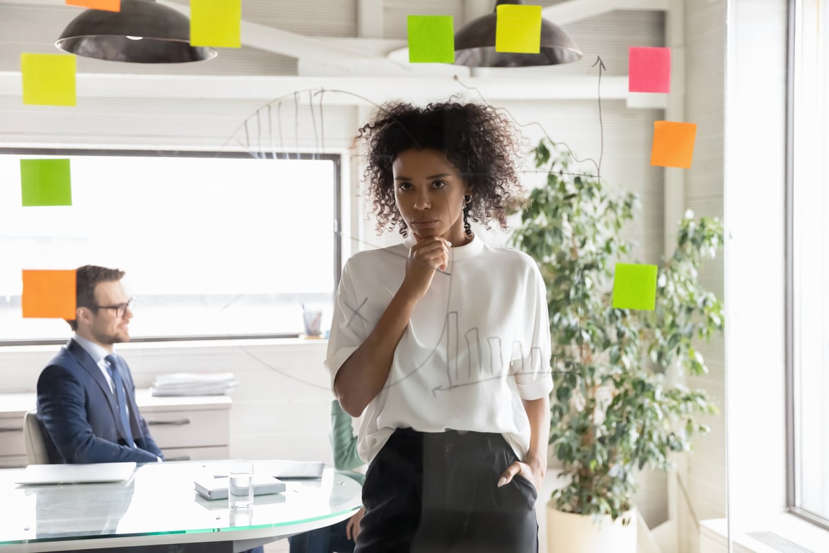 An investor stands in an office, looking at sticky notes placed on a wall.