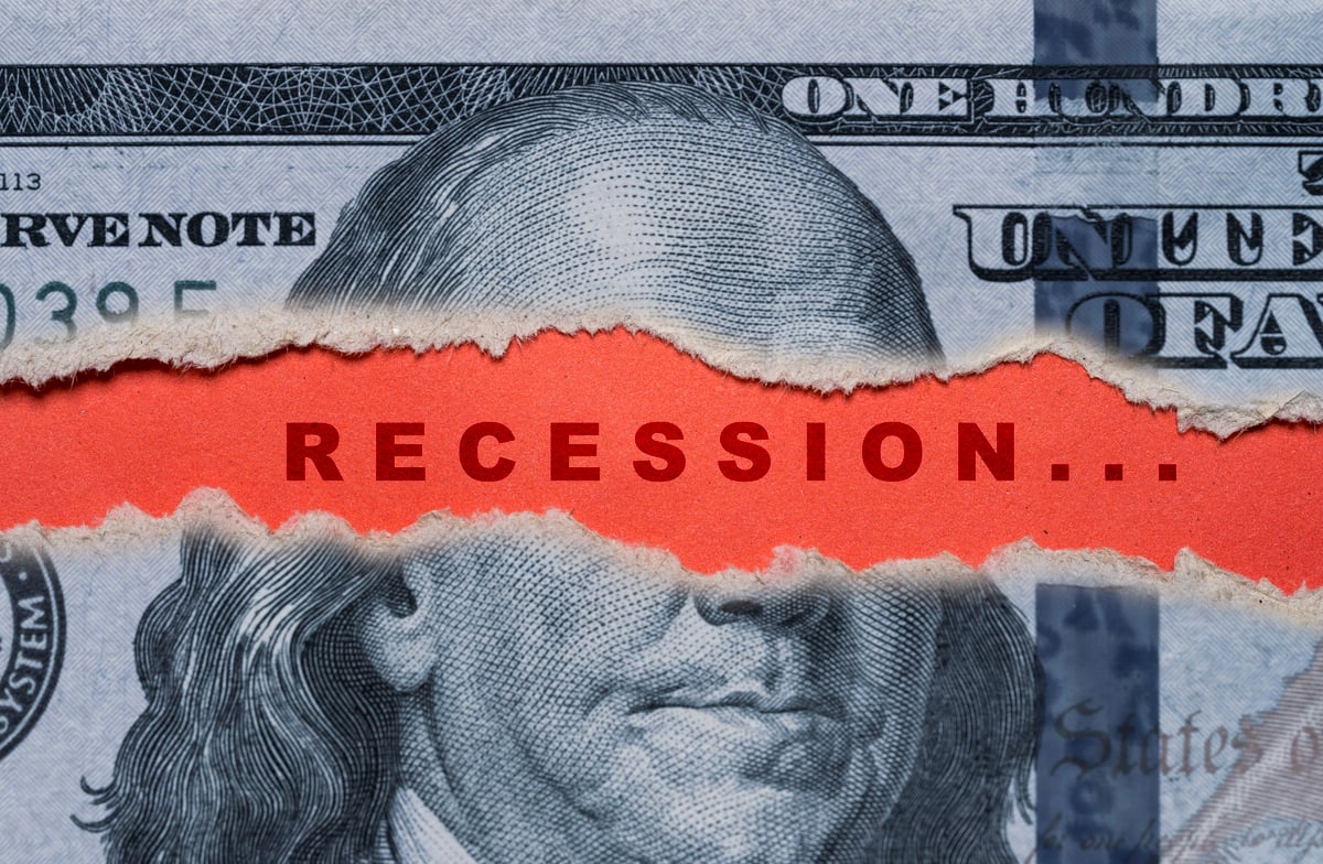 U.S. currency torn to reveal the word "recession" written in alarming red text.