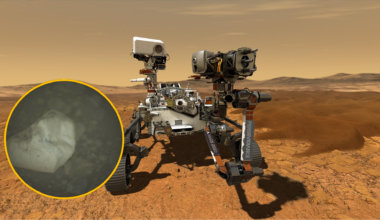 An illustration of Mars' Perseverance rover with a circular boxout showing a gray crystalline shape over a dark background