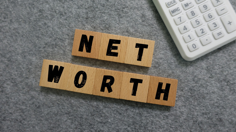 Net worth wooden blocks next to a calculator.