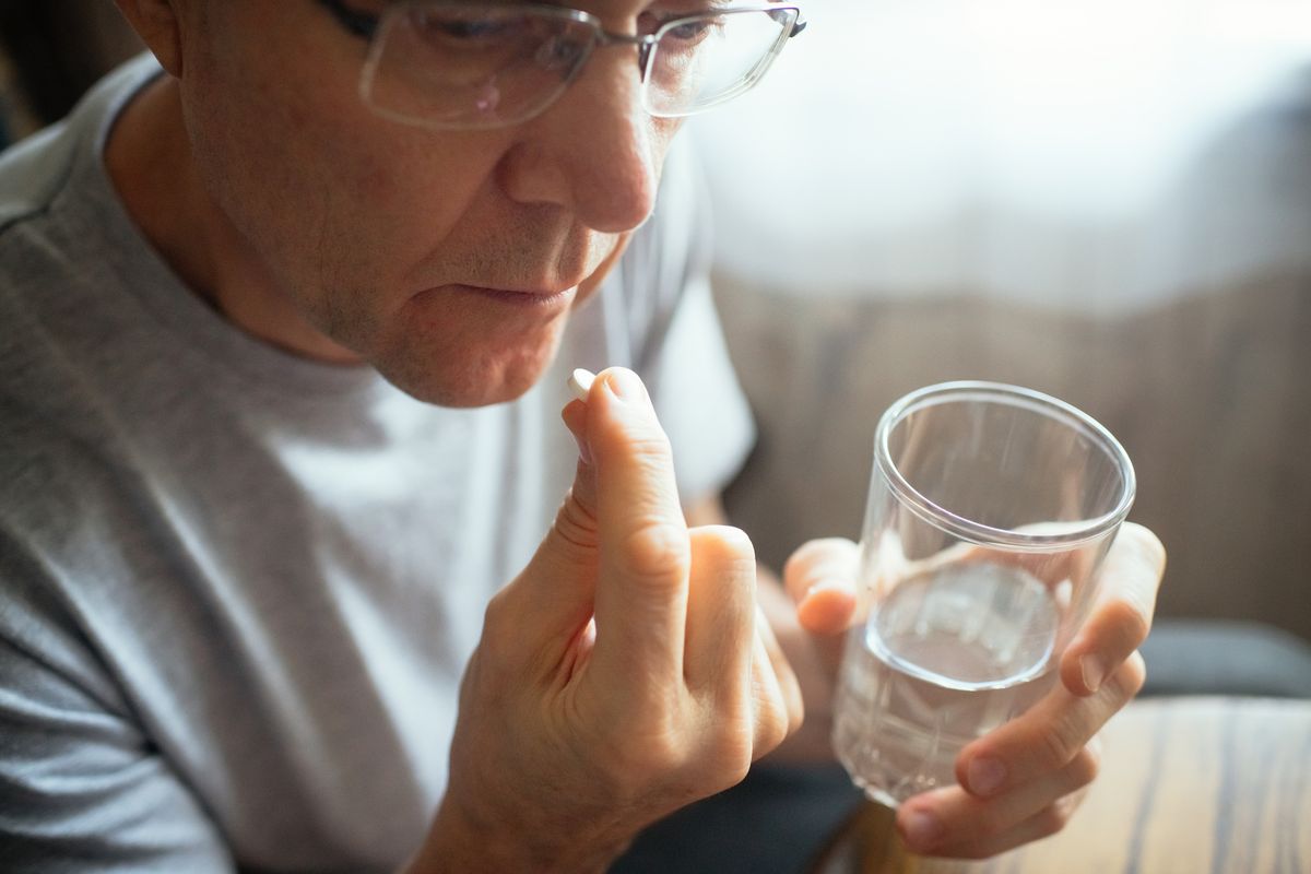 Senior man with a pill and a glass of water