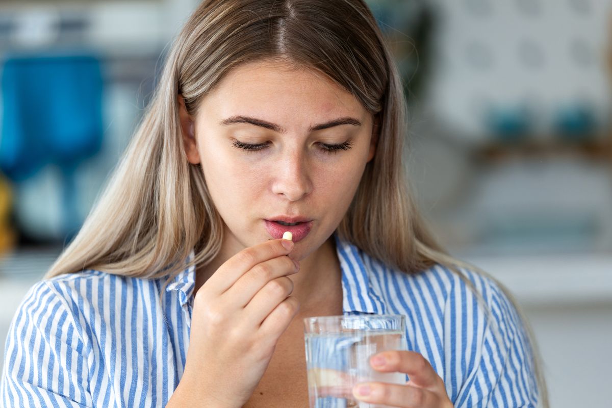 Woman taking medicine pill with water. Healthcare and medicine concept