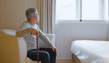 An Asian man is looking out the window from his house [GETTY IMAGE PRO]