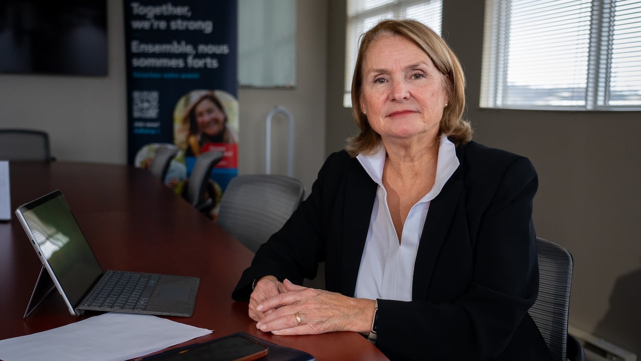 A woman sitting in a board room looking at the camera.