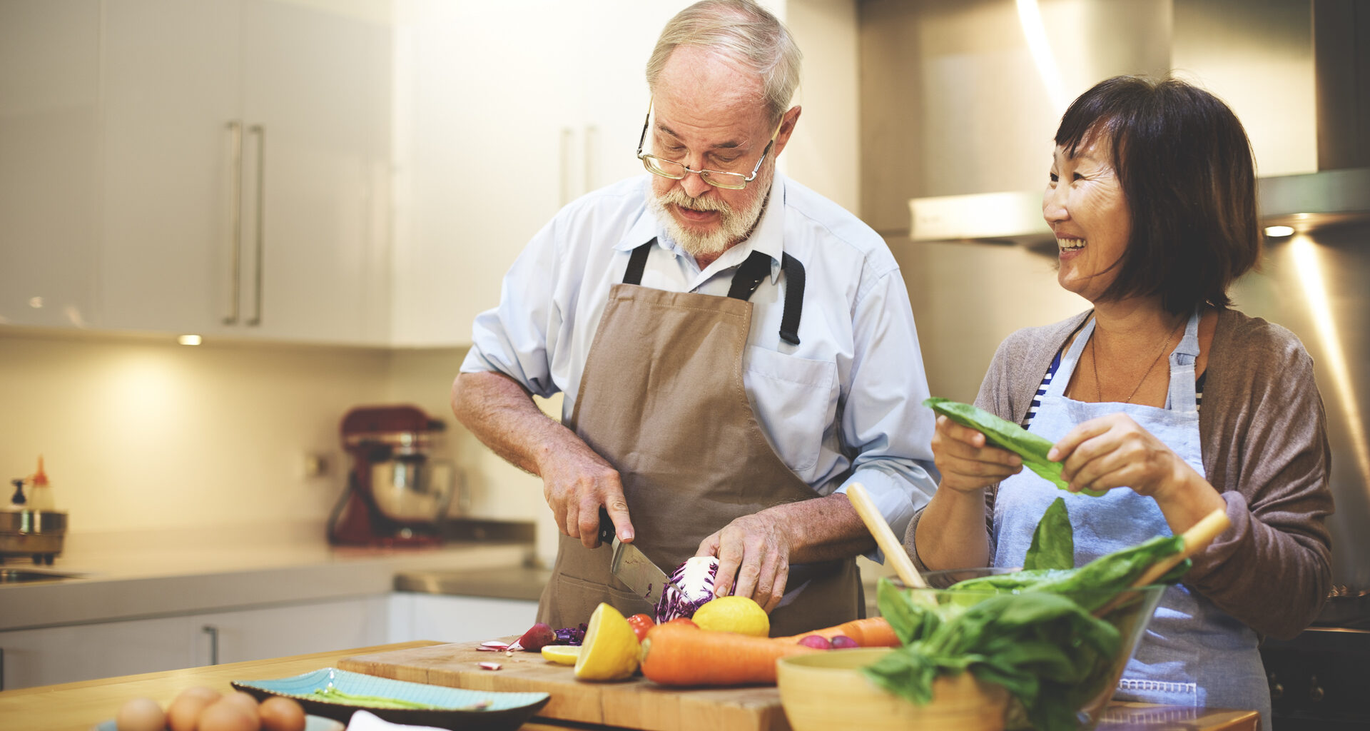 A senior man and woman cooking in kitchen in their house to save money on food costs.