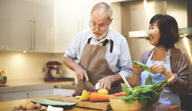 A senior man and woman cooking in kitchen in their house to save money on food costs.