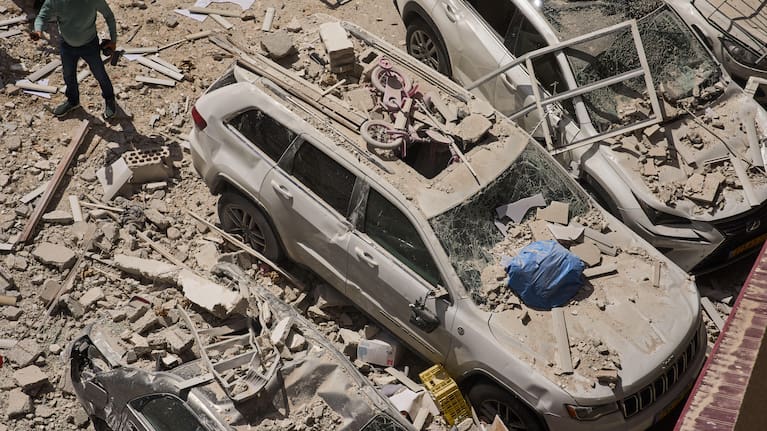 A man inspects the damage to cars and an apartment building struck by an Iranian missile in Ramat Gan, Israel. 